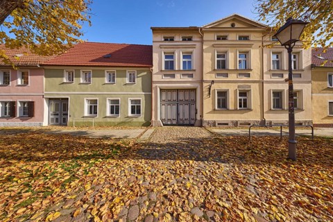 Cobbled street, residential building with lantern, foliage and autumn trees, blue sky,