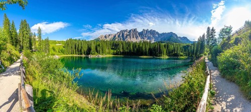Emerald waters reflecting latemar mountain range, creating breathtaking scenery at lake carezza, a