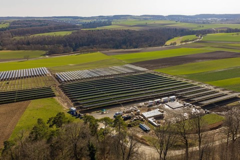 View of a large solar plant surrounded by fields and green hills, Agri PV Bau für Landwirtschaft,