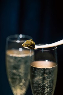 A close-up shot capturing Beluga caviar elegantly poised on a spoon, juxtaposed above two bubbling