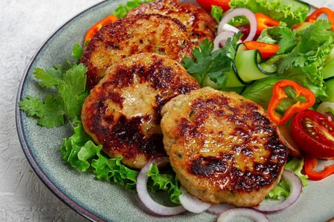 Fried chicken cutlets, minced chicken, with vegetables, on gray, with vegetable salad, top view,