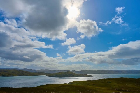 The sun shines through the clouds over a calm body of water, Loch Torridon, Balgy, Strathcarron,