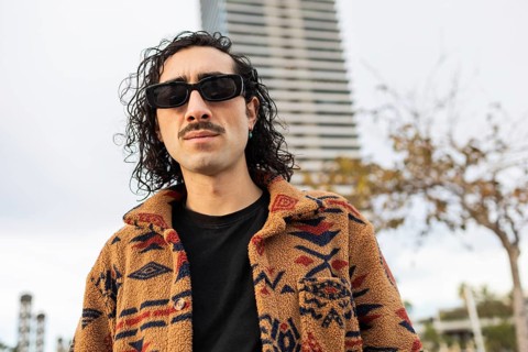 Stylish man with curly hair and sunglasses wears a warm, patterned fleece jacket He stands