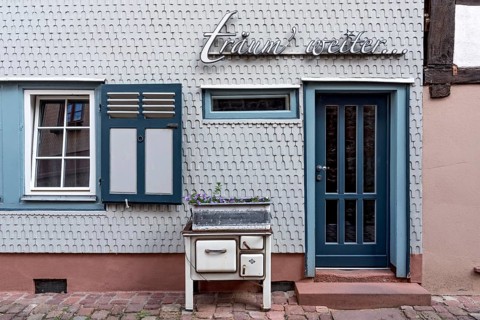 Residential house clad with wooden shingles, old oven for decoration in front of design hotel Die