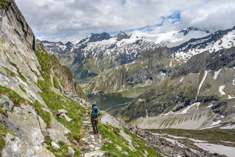 Mountaineer on a hiking trail in front of a picturesque mountain landscape, rocky mountain peaks
