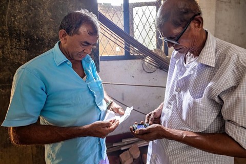 Two men talking in a room with sunlight, one holding medicine, the sapphire emeralds and precious