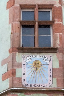 Old window and a sundial with the inscription 'CARPE DIEM' on a sandstone façade, Alsace, France