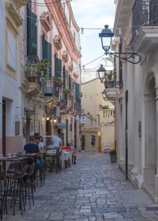 Narrow cobbled alley with cafés and historic Mediterranean-style buildings, Gallipoli, Apulia,