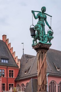 Scene with water bearer on the robber fountain in the historic old town of Freiburg im Breisgau,