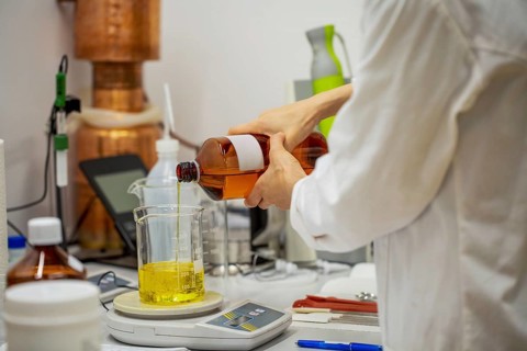 A laboratory setting where natural oil is being poured into a beaker, highlighting the process of