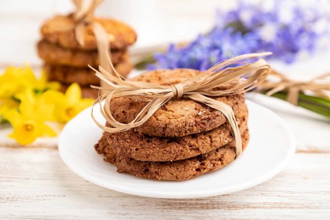 Oatmeal cookies with spring snowdrop flowers bluebells, narcissus and cup of coffee on white wooden