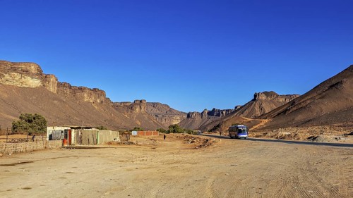 Lonely village in a vast desert landscape with steep rock formations, settlement in the Sahara in