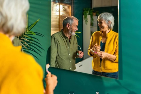 Reflection on the mirror of a caucasian senior couple washing teeth together at home