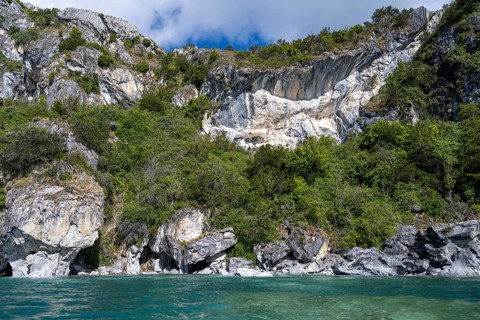 Marble rocks with overgrown rock walls on the turquoise waters of Lake General Carrera, Capillas de