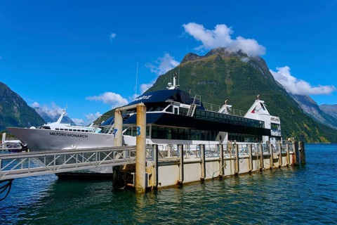 Passenger ship at the pier with majestic mountains in the background under a clear sky, summer,