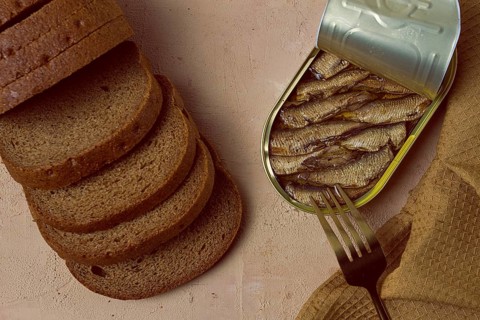 Sprats in butter, with black bread, canned smoked fish, open, close-up, top view, no people