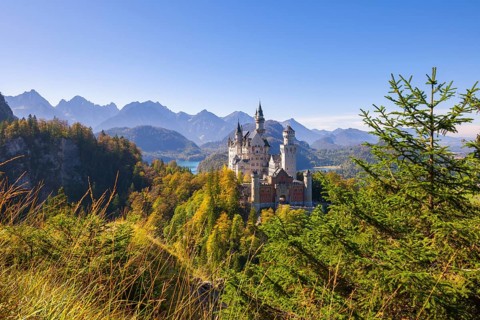 Neuschwanstein Castle in the midst of an impressive forest and mountain landscape, Schwangau,