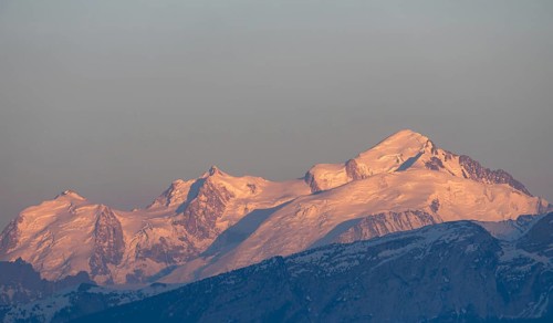 A breathtaking sunset casts a warm glow over the Swiss and French Alps, as seen from Geneva