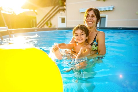 Mother and son playing and splashing in a home swimming pool, enjoying summer vacation together