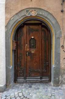 Massive wooden door with iron fittings and decorative coat of arms in the historic old town of