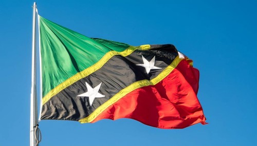The flag of St Kitts, Caribbean, fluttering in the wind, isolated against a blue sky