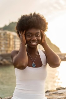 Vertical portrait of a happy african woman posing looking at camera next to the sea