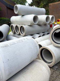 Several many stacked concrete pipes stored at the roadside Concrete pipes for sewer construction