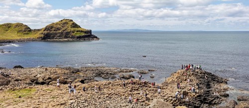 People climb basalt columns on the coast with a view of the sea, Giant Causeway