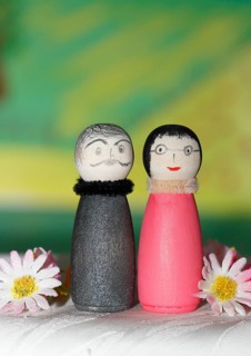 Funny painted wooden cone man and woman in front of a colourful painted background, North