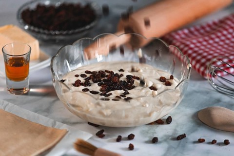 Sultanas fall into a bowl of curd cream, surrounded by ingredients and kitchen utensils
