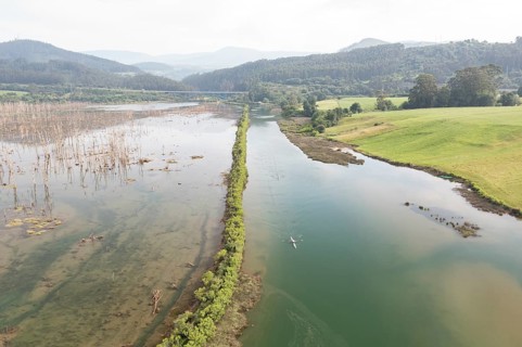 Aerial view of a serene river winding through lush wetlands and green fields near San Vicente de la