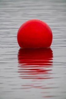 Red buoy on a lake, marker buoys for water sports, regattas, rowing, canoeing, kayaking, symbolic