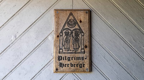 Wooden plaque with medieval drawing and the words 'Pilgrims Hostel' on a wooden door, Arteid Vestre