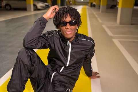 Modern musician sitting posing on a garage smiling at camera