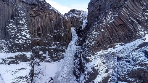 The beautiful Hengifoss waterfall frozen in the cold winter of Iceland, volcanic cliffs