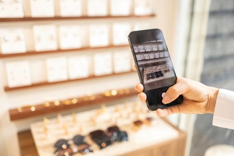 A person is taking a photo with a smartphone in a stylish bag store, capturing the elegant display