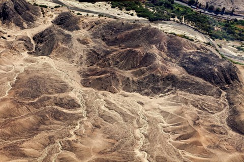 Aerial view of a desert landscape with hills, a river course and sparse vegetation, The landscape