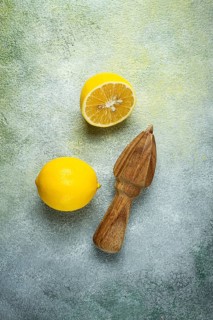 Wooden citrus reamer, manual lemon juicer, made of acacia wood, with citrus fruits on the table,