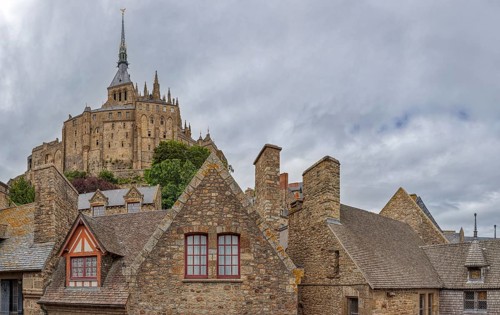 Historic buildings with an impressive church in the background, under a cloudy sky, Le