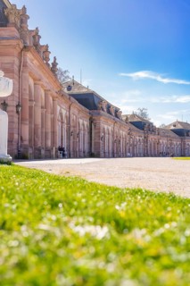 Baroque building with blue sky and green meadow in the foreground, Schwetzingen Palace Gardens,