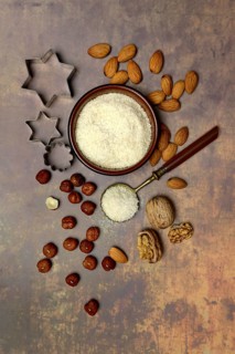 Grated coconut in a bowl and spoon, various nuts and cookie cutters