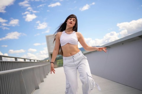 Energetic female caucasian casual dancer performing urban choreography on a bridge in a sunny day
