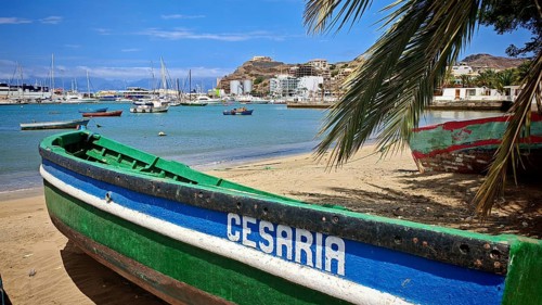 View of small green, colourful boat with inscription 'Cesaria' on the beach with calm water and