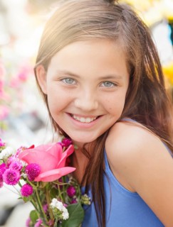 Adorable happy young blue eyed girl holding a fresh cut floral bouquet at the farmers market