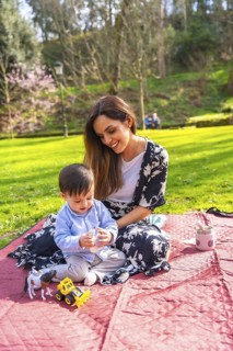 Mother and baby enjoying a picnic in the park, playing with toys on a blanket on a sunny day