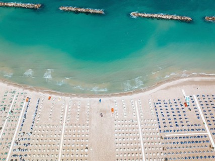 Stunning aerial perspective of San Benedetto beach, featuring rows of sun loungers and vibrant