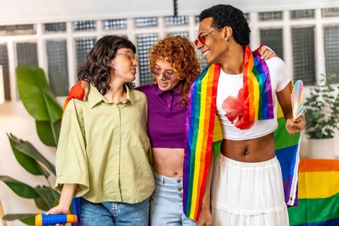 Multi-ethnic lgbt friends singing karaoke and partying with rainbow flags at home