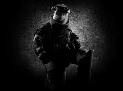 Military man in a protective sapper suit is kneeling and is preparing to neutralize the bomb.
