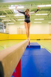 Female athlete balancing on a balance beam in a bright yellow hall, Gymnastics, Calw, Germany