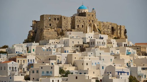 View of a historic fortress on a hill with white houses and blue roofs, Querini Castle, Chora,